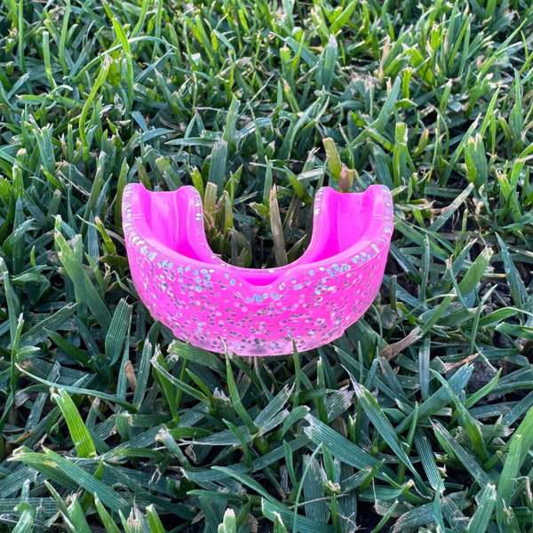 Pink glitter mouthguard on grass