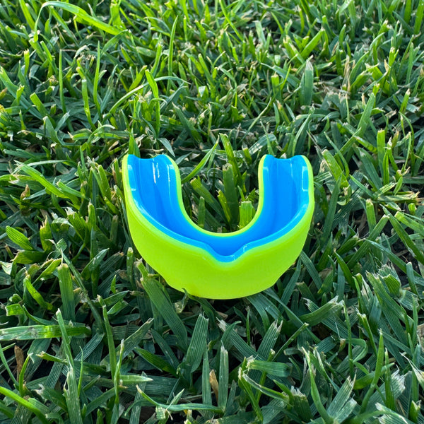 neon Blue and highlighter yellow mouthguard on grass
