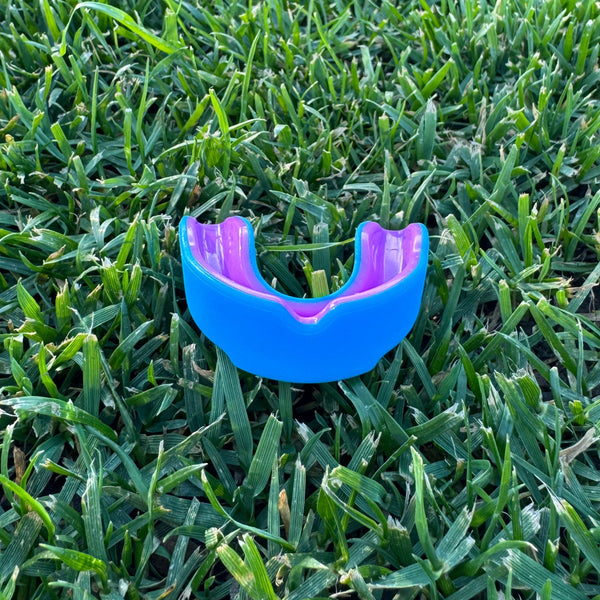 neon blue and purple mouthguard on grass