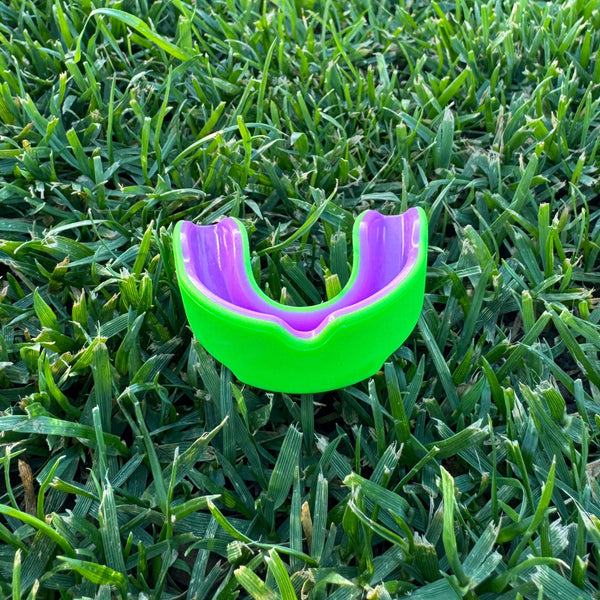 neon green and purple mouthguard on grass